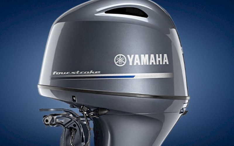 A Yamaha four-stroke outboard marine engine with a gray cowling against a blue sky background.