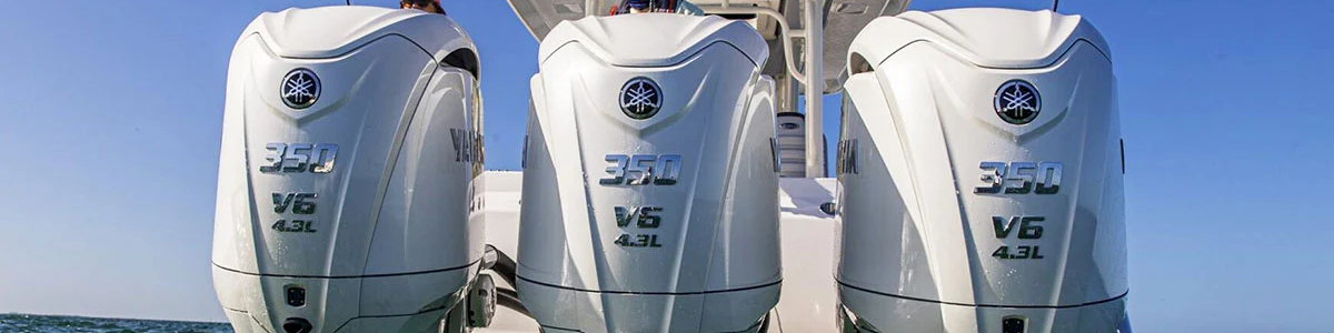 Three white outboard motors labeled 350 V6 on a boat, with a captain at the helm against a clear blue sky.