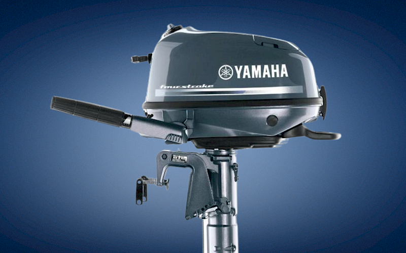 A Yamaha four-stroke outboard boat motor on a stand against a blue sky background.