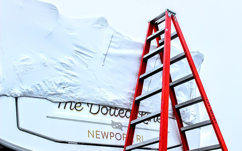 A red ladder stands beside a white inflatable structure, with partial printed text (&ldquo;the Voted&rdquo;/&ldquo;NEWPORT&rdquo;) visible behind it.