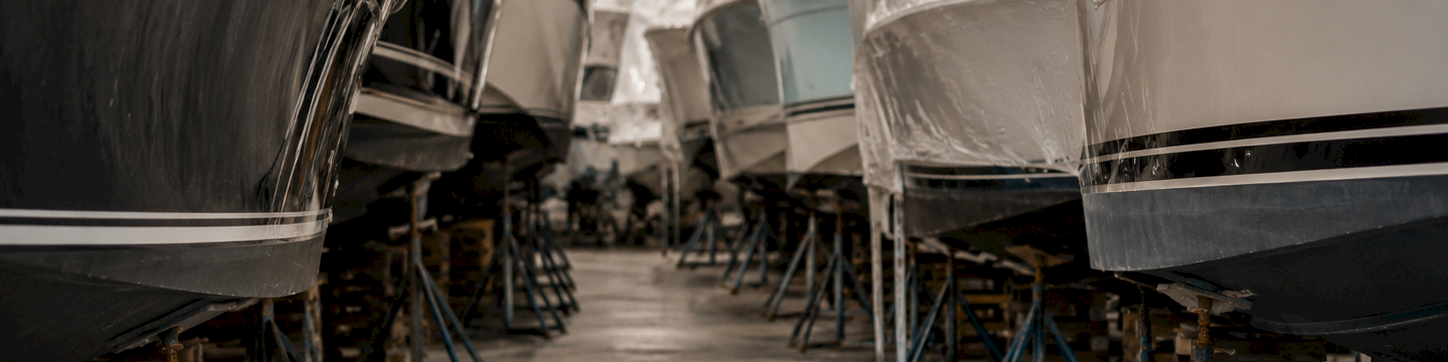 A factory workshop corridor with cars on stands, their bodies wrapped in plastic under repair or assembly.