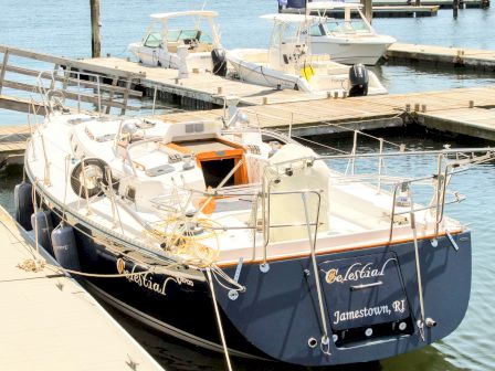 A luxury motor yacht is docked at a marina, with another boat moored beside it on calm water.