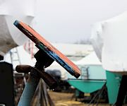 Close-up of a rusty, paint-chipped wooden plank on a metal stand in a cluttered workshop.